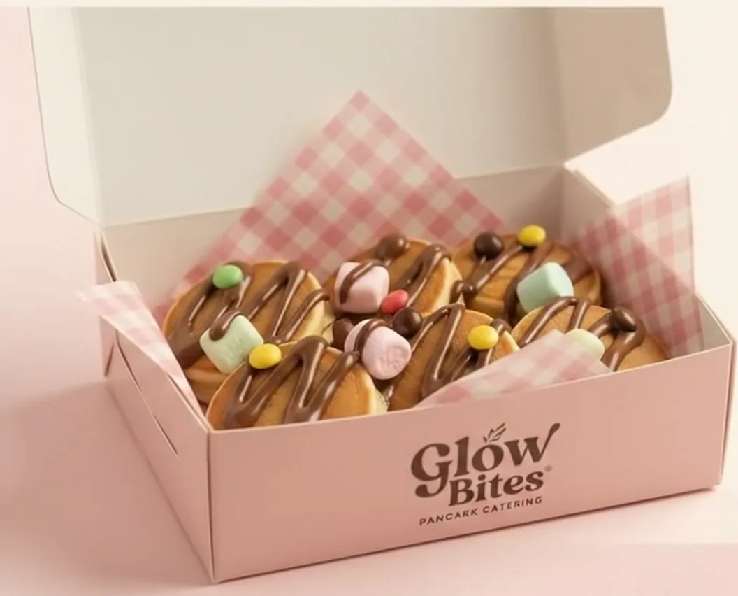 A pink Glow Bites box of mini pancakes, chocolate and colorful toppings